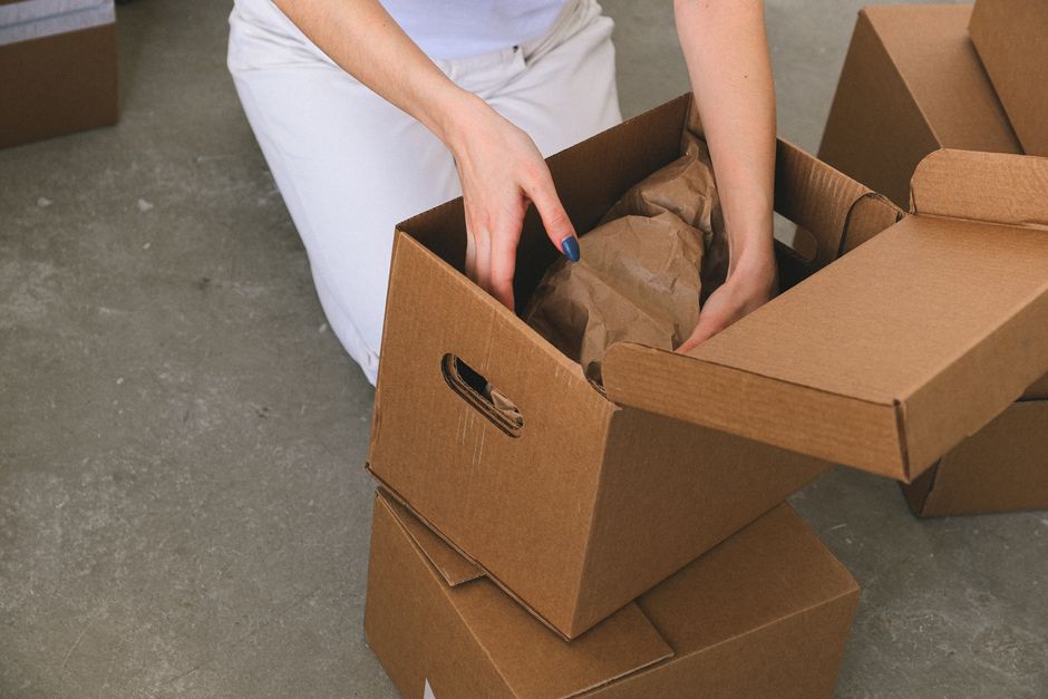Movers carefully wrapping and packing cardboard boxes